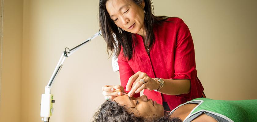 Woman performing acupuncture on patient