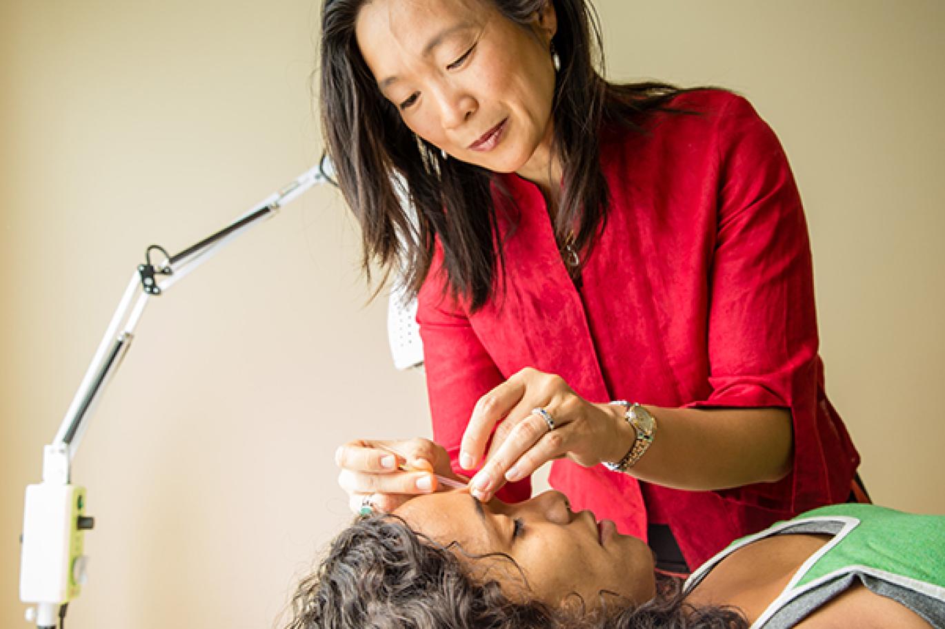 Woman performing acupuncture on patient